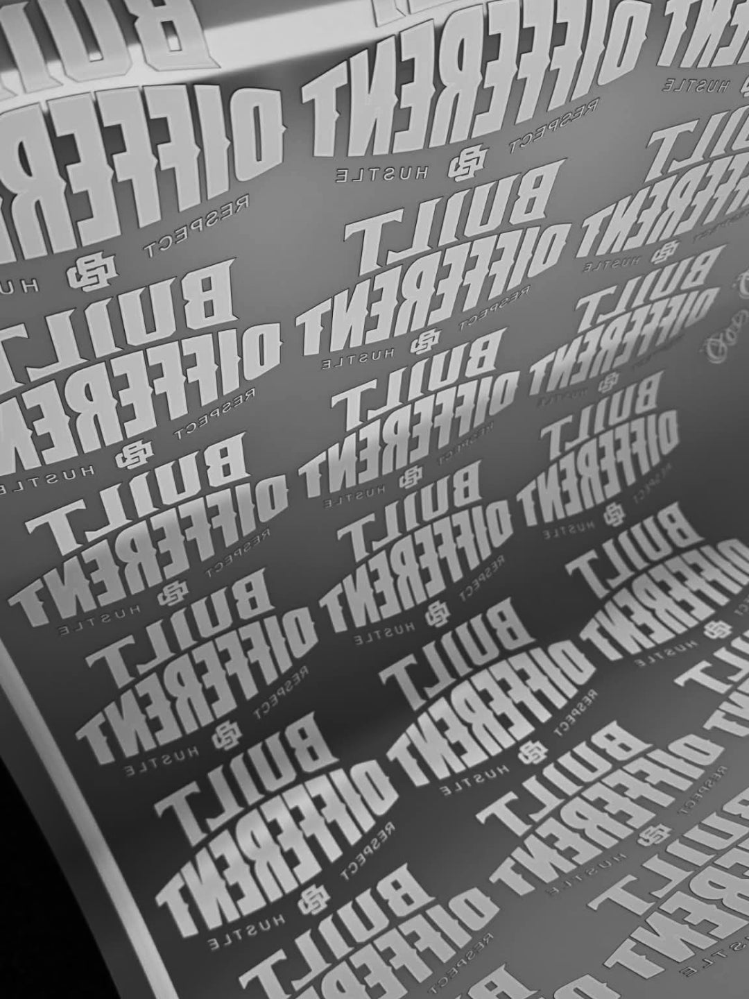 Close-up of a product with 'BUILT DIFFERENT' branding on clear DTF print film, printed by Ōtautahi Print Co.